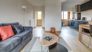 Un espacio habitable moderno con sofá, una mesa de centro y una zona de cocina.