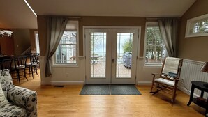 Amplia sala de estar con piso de madera, un sofá estampado, un sillón mecedor y un comedor con sillas y una mesa.