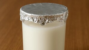 Un verre recouvert d’un couvercle en papier métallisé, posé sur une surface en bois.