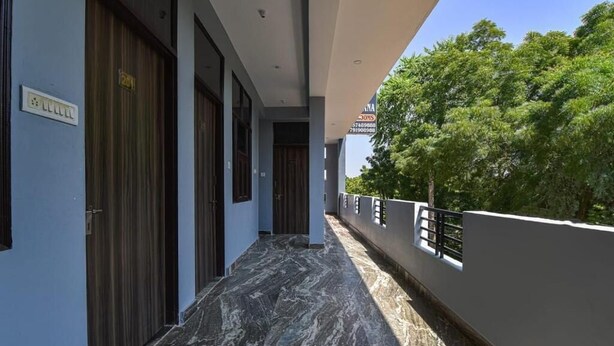 Un couloir doté d’un sol en marbre, de portes en bois et d’un balcon agrémenté d’une balustrade.