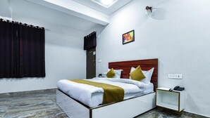 Une chambre d’hôtel moderne équipée d’un lit, d’une table de chevet et d’un luminaire fixé au mur.