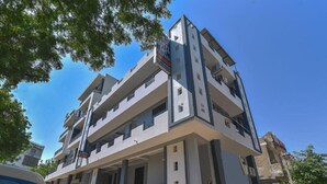 Un hôtel à plusieurs étages doté de balcons, d’une entrée couverte et d’un parking où sont stationnées des motos.