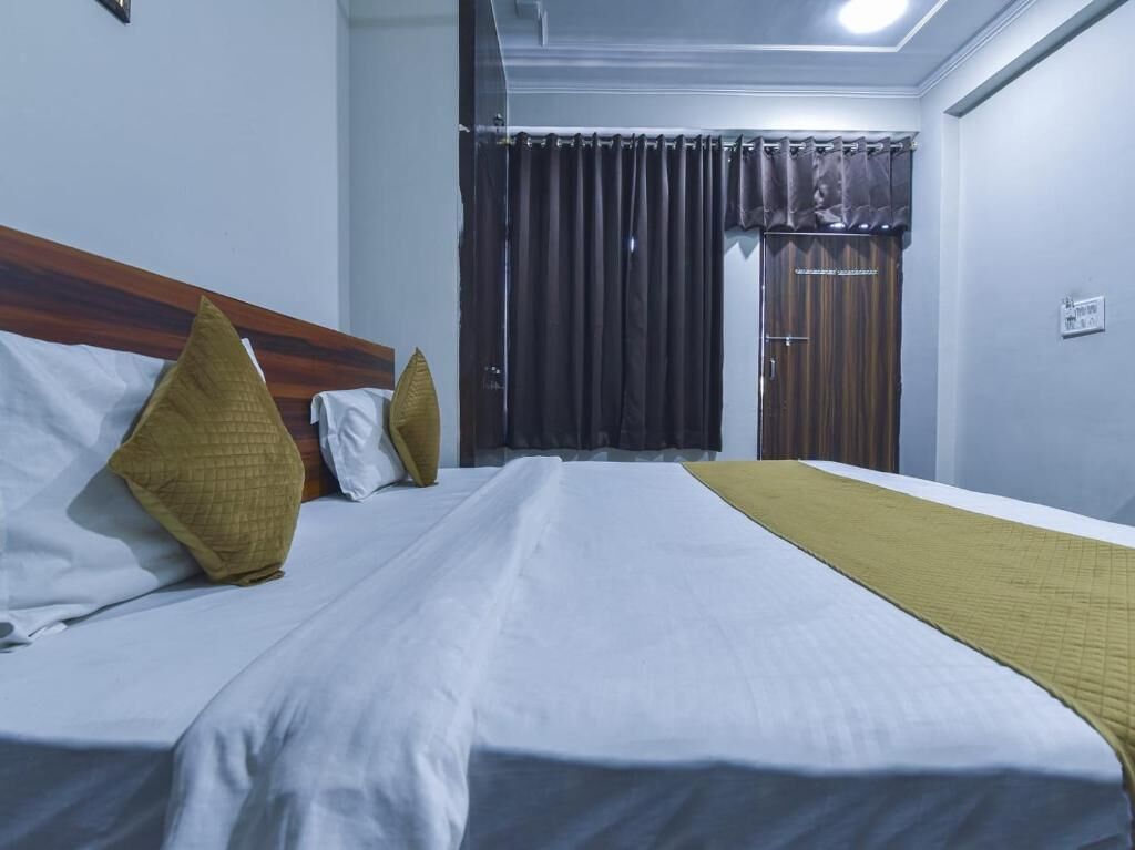 A hotel room with a bed, curtains, a wooden headboard, and a door.