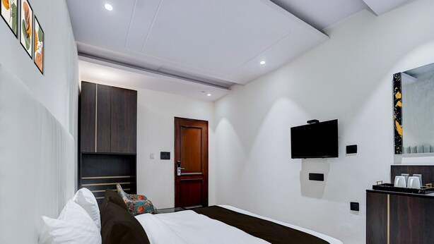 A modern hotel room with a bed, a TV, a wardrobe, and a desk with a mirror. - Deluxe With Twin Bed Hotel Unistar (New Delhi)