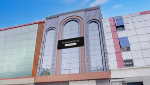 A modern building with a sign reading 'TOWNHOUSE' and a company service symbol. - Deluxe With Twin Bed Hotel Unistar (New Delhi)