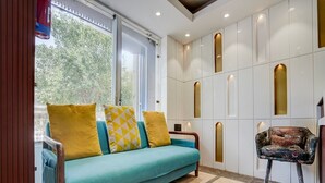 A room with a teal sofa, yellow and white patterned cushions, a patterned armchair, and a tiled floor. - Deluxe With Twin Bed Hotel Unistar (New Delhi)