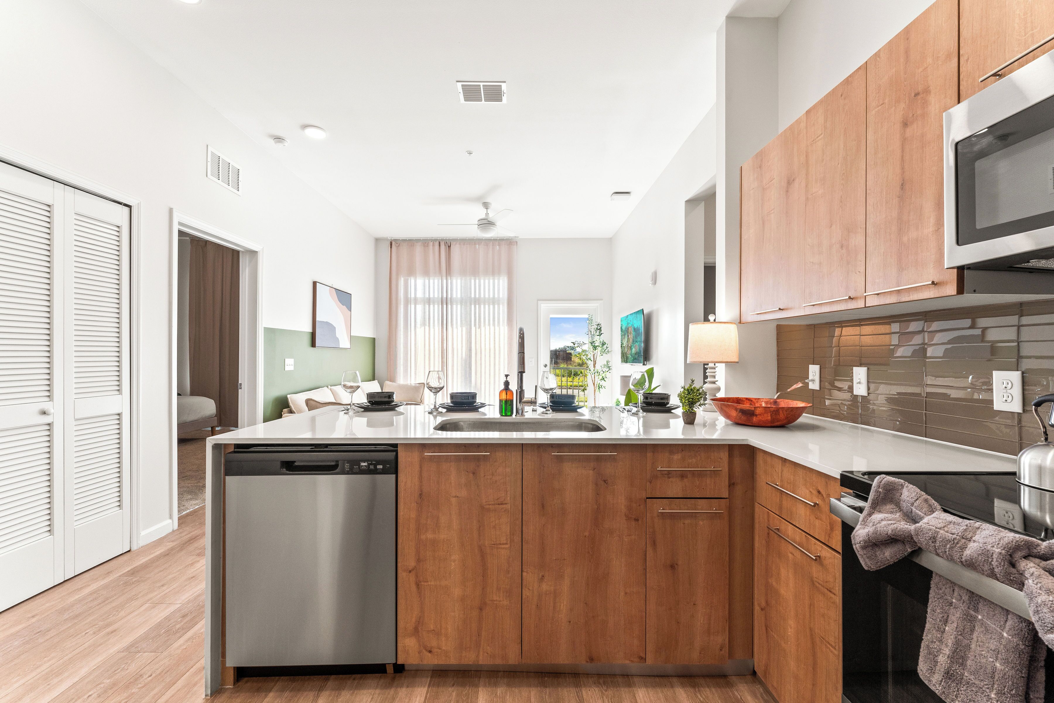 A modern kitchen with wooden cabinets, a dishwasher, a microwave, and a sink.