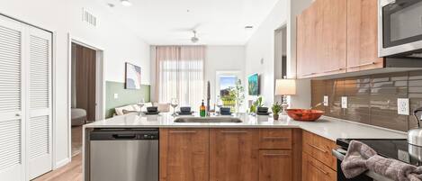 A modern kitchen with wooden cabinets, a dishwasher, a microwave, and a sink.