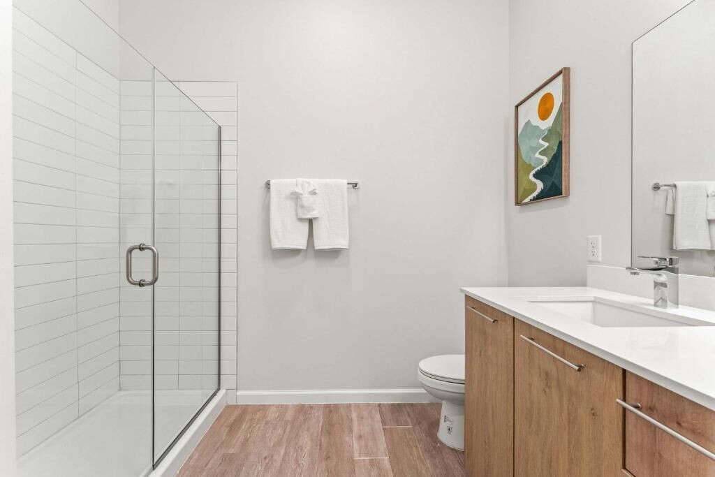A modern bathroom with a glass shower enclosure, a toilet, and a vanity with a mirror.