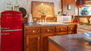 Une cuisine avec un réfrigérateur Galanz rouge, des placards en bois, un four à micro-ondes blanc et un évier.