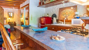 Une cuisine dotée d’un plan de travail en marbre, d’un réfrigérateur rouge, d’une cuisinière à gaz et d’un four à micro-ondes.