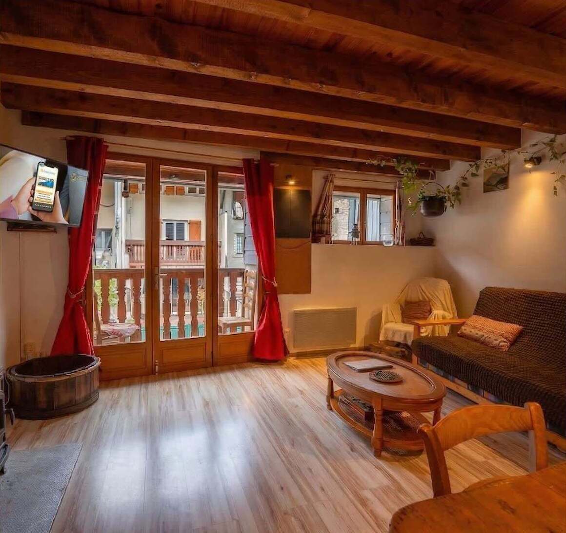 Uma sala de estar aconchegante com teto de madeira, um sofá, uma mesa de centro e uma televisão.