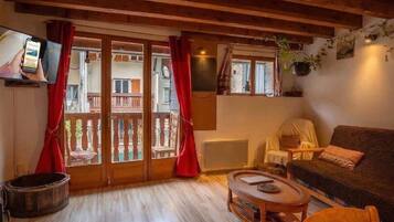 Uma sala de estar aconchegante com teto de madeira, um sofá, uma mesa de centro e uma televisão.