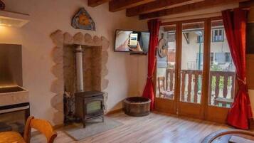 Um quarto aconchegante com lareira de pedra, televisão e teto de madeira.