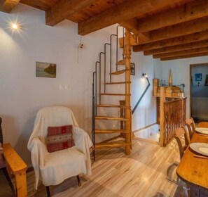 A wooden interior with a spiral staircase, a dining area, and a cozy chair. - Chez Ludo I T4 I Francin (Porte-de-Savoie)