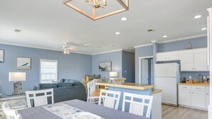 Una cocina moderna con armarios blancos, una isla central y un comedor con mesa para cuatro.