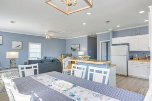 A modern kitchen with white cabinets, a central island, and a dining area with a table set for four. - Beautiful 3-bedroom house with Hot Tub in charming Crystal Beach (Crystal Beach)