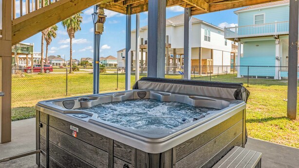 Un jacuzzi bajo una pérgola de madera con vistas a edificios residenciales.