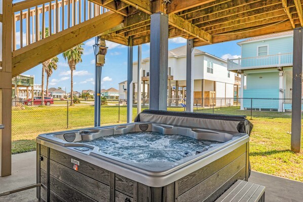 A hot tub under a wooden pergola with a view of residential buildings. - Beautiful 3-bedroom house with Hot Tub in charming Crystal Beach (Crystal Beach)