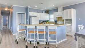 Una cocina con isla central, armarios blancos y una pared azul decorativa.