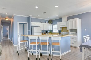 A kitchen with a central island, white cabinets, and a blue accent wall. - Beautiful 3-bedroom house with Hot Tub in charming Crystal Beach (Crystal Beach)