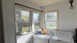 Una sala de lavandería con dos lavadoras, un tendedero y una ventana que ofrece vistas al exterior.