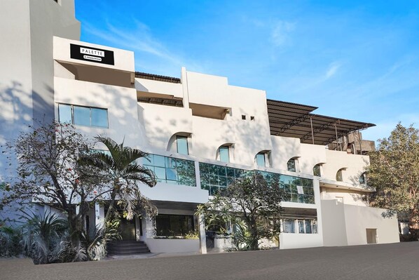 A modern building with a sign reading 'PALETTE.' It features a multi-story structure with large windows and a covered outdoor area. - Deluxe Country Club (Surat)
