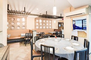 A dining area with round tables, black and white checkered tablecloths, and black chairs. - Deluxe Country Club (Surat)