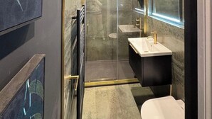 Un baño moderno con cabina de ducha de vidrio, tocador con espejo y retrete.