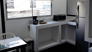 A modern kitchen with a built-in microwave, a refrigerator, a ceiling fan, and a window with a view of the outside. - Costa Rica Walk In (San José)