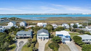 Un área residencial con casas, vista despejada al océano y una playa de arena.