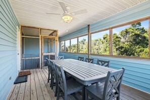 A covered porch with a table and chairs, a ceiling fan, and a view of trees. - Charming 4BR Cottage | Walk to Beach | Outdoor Space | Atlantic Beach (Atlantic Beach)