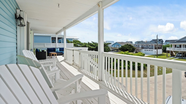A covered porch with Adirondack chairs, a small seating area, and a view of neighboring houses. - Charming 4BR Cottage | Walk to Beach | Outdoor Space | Atlantic Beach (Atlantic Beach)