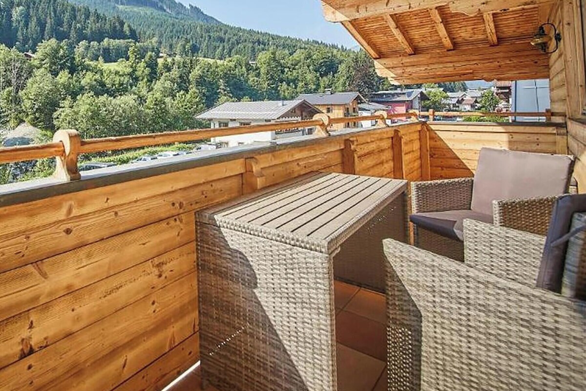 A wooden balcony with wicker furniture, overlooking a mountainous landscape.