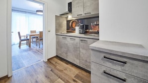 Una cocina moderna con armarios grises, una cafetera y un comedor con mobiliario de madera.