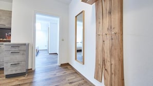 Un pasillo con suelo de madera, un armario y un espejo en la pared.