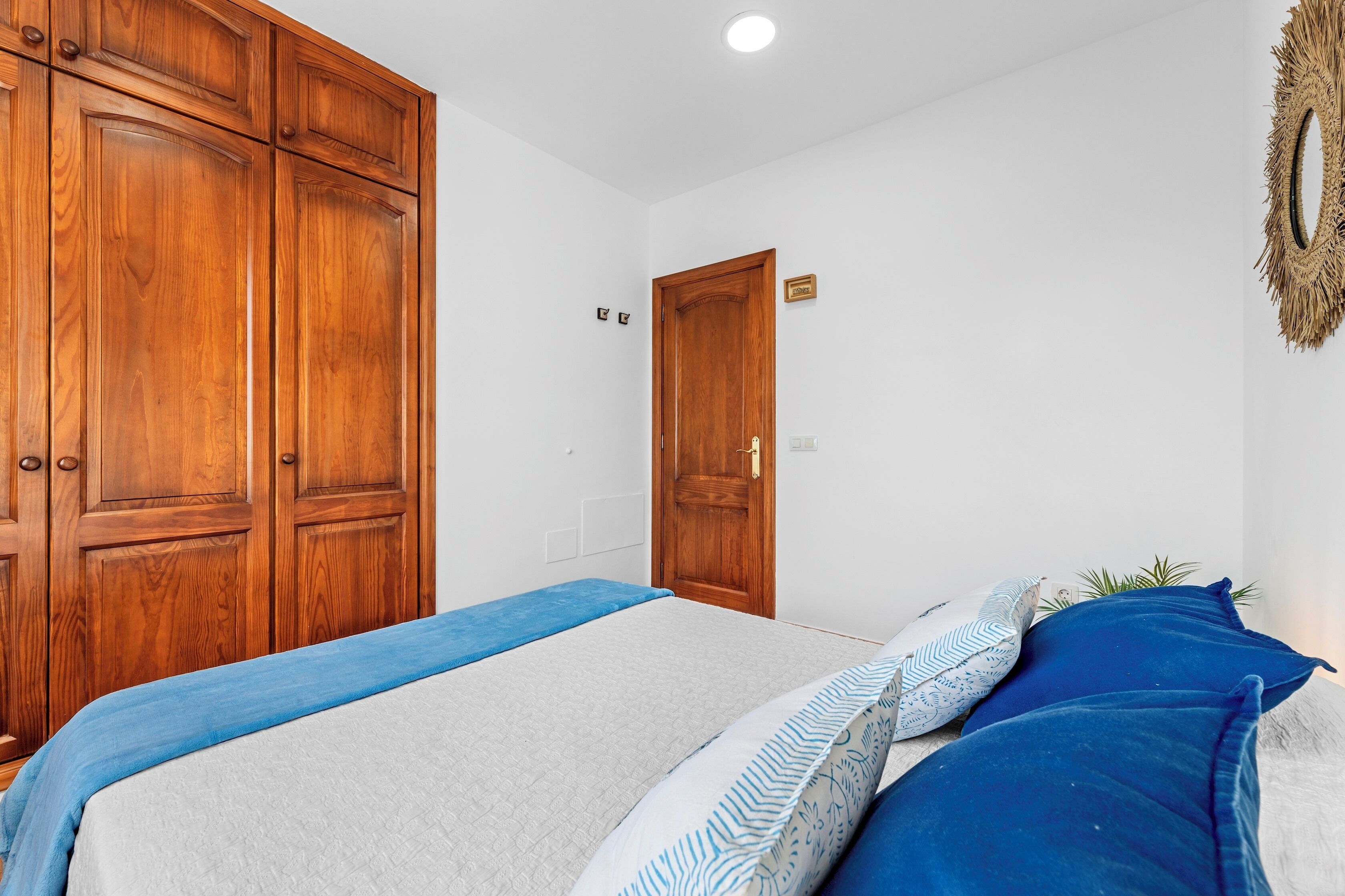 A bedroom with a bed, wooden wardrobe, and a door.
