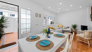 Una sala de estar moderna con comedor, paredes blancas y un ventanal grande.