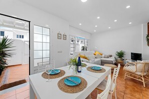 A modern living room with a dining area, white walls, and a large window. - Home2Book Stunning Terrace & BBQ House Playa Honda (Playa Honda)