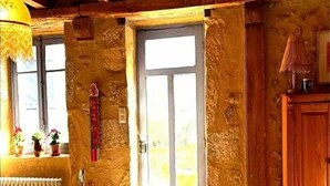 A rustic room with a wooden ceiling, a stone wall, a wooden door, a radiator, a small table, and a cabinet. - THE FARM: 145m2, 6 pers-3 bedrooms swimming pool/river/isolated/ Montignac Lascaux at 9.2km (Saint-Léon-sur-Vézère)