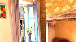 A room with a table, chairs, a window with curtains, a vase with flowers, and a stone wall. - THE FARM: 145m2, 6 pers-3 bedrooms swimming pool/river/isolated/ Montignac Lascaux at 9.2km (Saint-Léon-sur-Vézère)