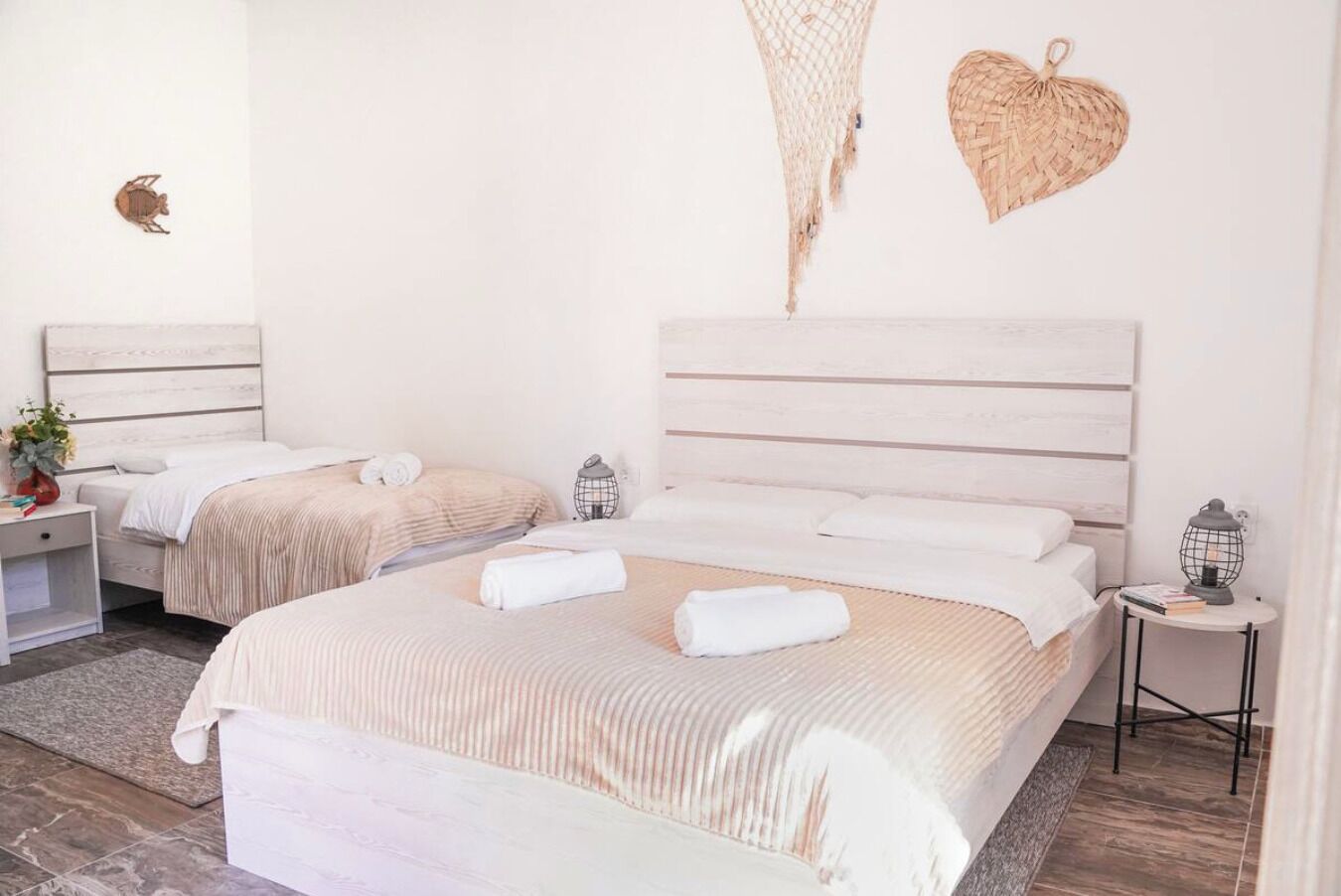 Une chambre avec deux lits, une table de chevet avec une lampe, une étagère fixée au mur et une décoration murale.