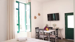 Ein Hotelzimmer mit einem Bett, einem Schreibtisch mit Stuhl, einem Fernseher und einem Fenster mit Vorhängen.