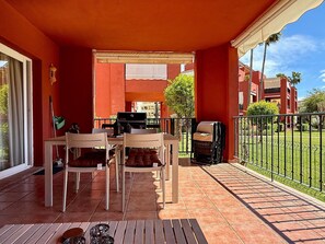 A covered outdoor patio with a grill, chairs, and a table. - Pool view private terrace ground floor Mijas Costa with barbecue by Solrentspain (Mijas Costa)