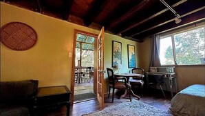 A room with a bed, a desk, a chair, a dining table, and a large window.