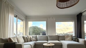 A modern living room with a sectional sofa, a round coffee table, and a woven ottoman. - Villa Ibiza by Solrentspain - La Cala de Mijas (Mijas Costa)
