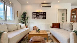 Un salon avec deux canapés, une table basse, une plante en pot et un climatiseur fixé au mur.