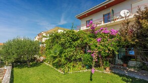A residential building with a garden, a balcony with a satellite dish, and a stone wall. - Vacation apartment in a quiet location, not far from the sandy beach (Crikvenica)