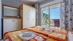 A bedroom with a bed, a wardrobe, and a view of the outside. - Vacation apartment in a quiet location, not far from the sandy beach (Crikvenica)