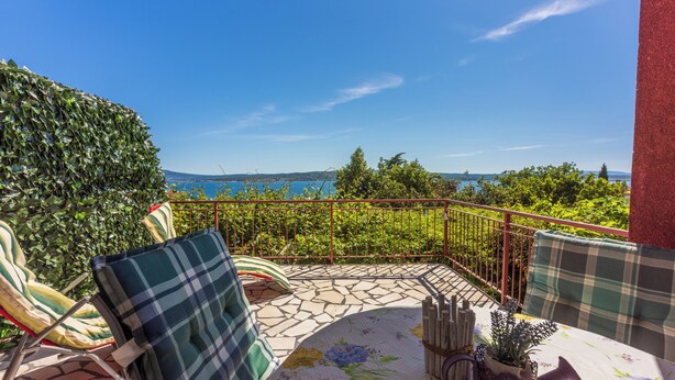A balcony with a view of the sea, a table with a floral tablecloth, and two chairs with plaid cushions. - Vacation apartment in a quiet location, not far from the sandy beach (Crikvenica)